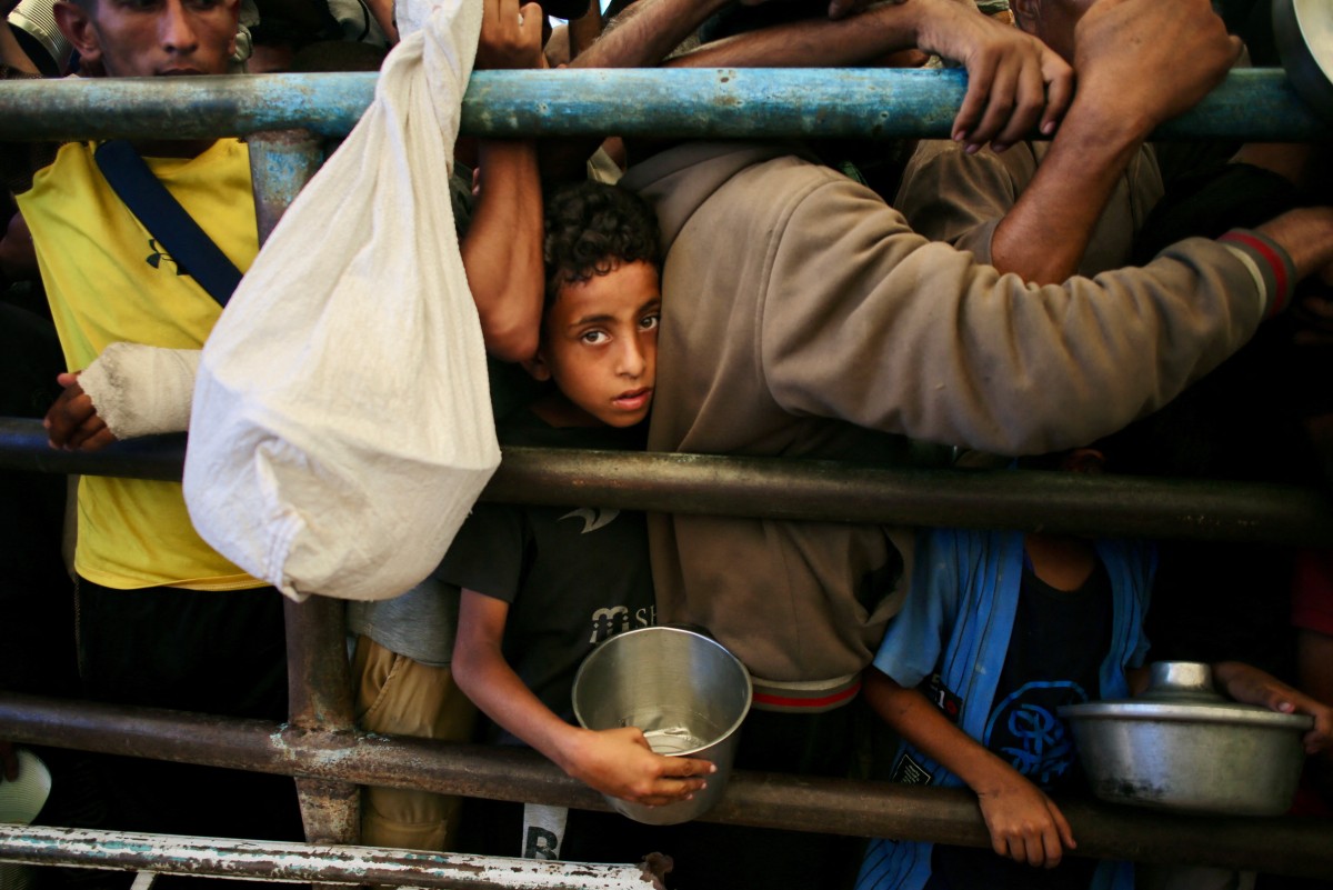 Un niño en Gaza haciendo fila para recibir comida en una multitud.