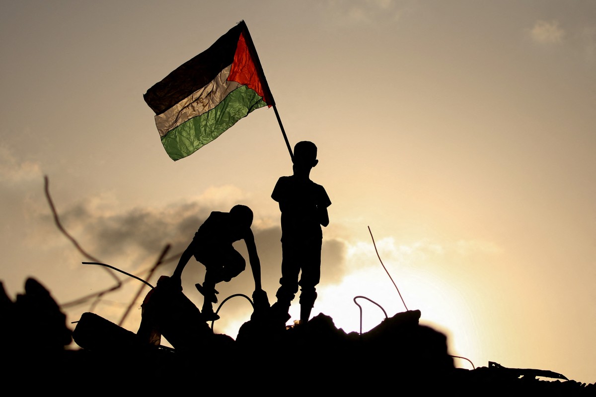 Niños palestinos desplazados ondean la bandera nacional palestina mientras él permanece de pie sobre los escombros de un edificio destruido en el campamento de refugiados de Bureij, en el centro de la Franja de Gaza, el 22 de septiembre de 2025. Gran Bretaña, Australia, Canadá y Portugal reconocieron el estado Palestino el 21 de septiembre, un giro histórico en décadas de política exterior occidental que provocó la ira inmediata de Israel y la reprimenda de Estados Unidos.