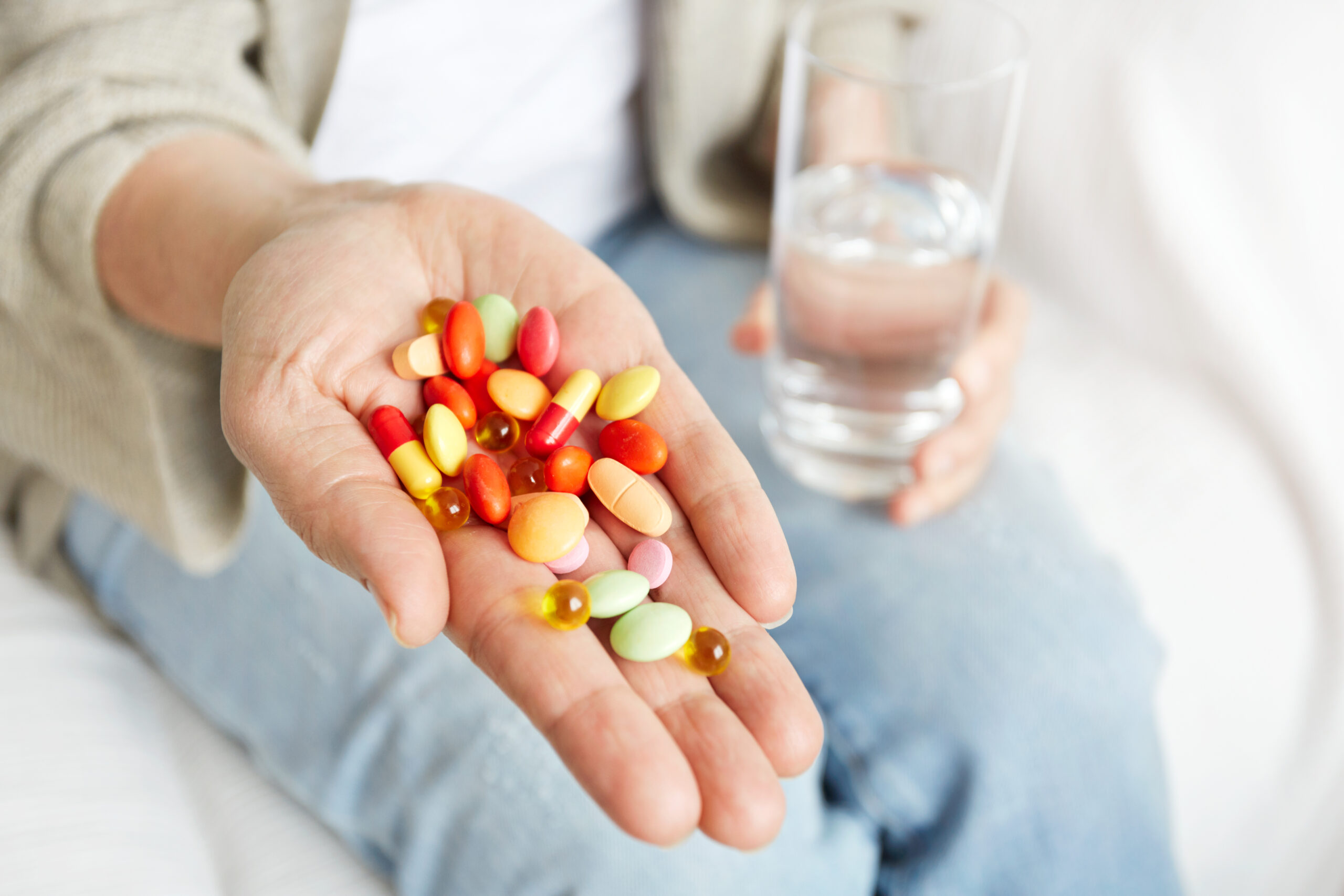 Píldoras, tabletas, vitaminas y medicamentos se amontonan en manos maduras, vista de cerca.